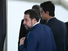 Guilherme Boulos (PSol) olhando para o lado, sério, caminhando, de costas