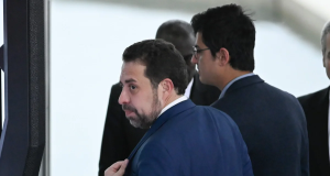 Guilherme Boulos (PSol) olhando para o lado, sério, caminhando, de costas