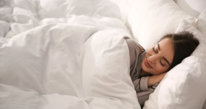 Mulher dormindo coberta com expressão serena