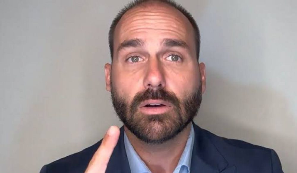 Eduardo Bolsonaro em close, com expressão de alerta e apontando pra cima