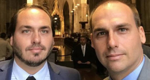 Carlos Bolsonaro (PL) e Eduardo Bolsonaro (PL) olhando para a câmera, sérios, lado a lado