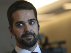 Eduardo Leite em close, sério, com o olhar para o lado