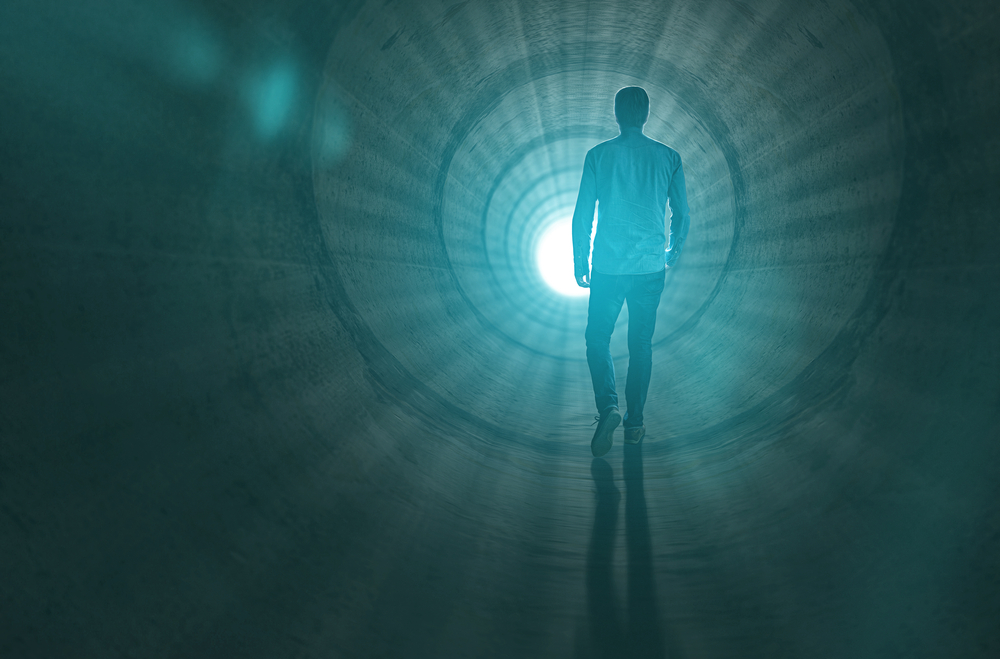 Homem caminhando de costas em direção a luz