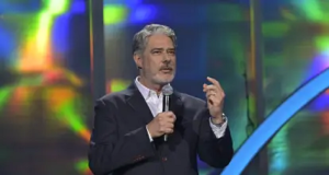 William Bonner falando em microfone, em pé, gesticulando, sem olhar para a câmera