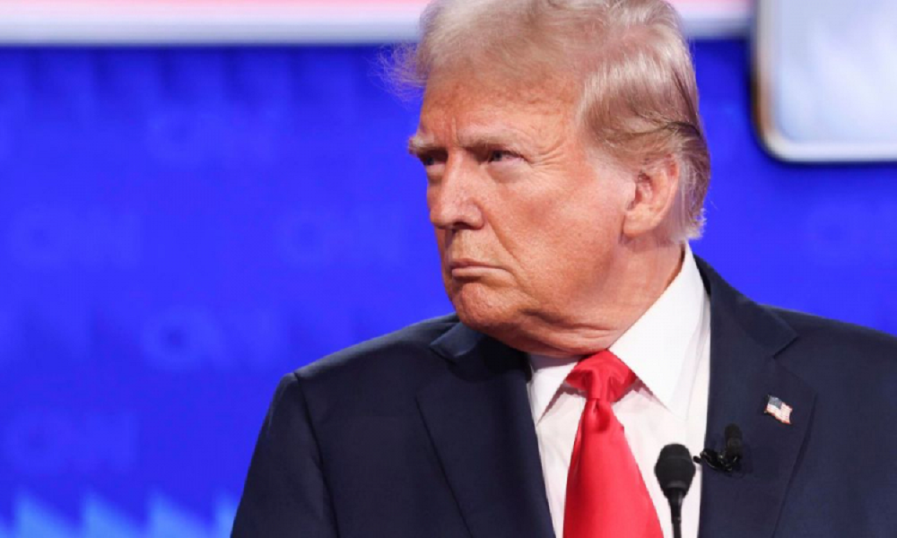 Donald Trump sério, de perfil, no canto direito de foto