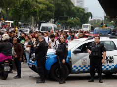 Policiais em rua do Rio, em meio a carros, com pessoas passando