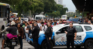 Policiais em rua do Rio, em meio a carros, com pessoas passando