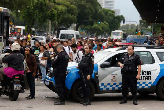 Policiais em rua do Rio, em meio a carros, com pessoas passando