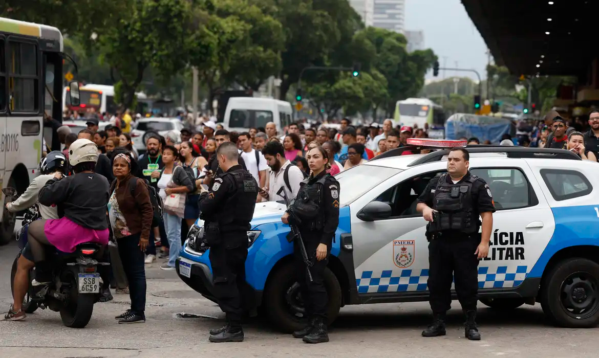 Policiais em rua do Rio, em meio a carros, com pessoas passando