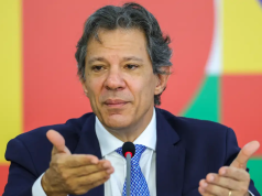 O ministro da Fazenda, Fernando Haddad, falando e gesticulando sem olhar para a câmera, sério