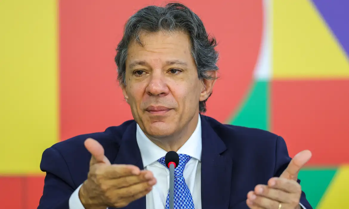 O ministro da Fazenda, Fernando Haddad, falando e gesticulando sem olhar para a câmera, sério