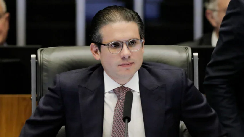 O presidente da Câmara, Hugo Motta, sério, de óculos, sentado, sem olhar para a câmera