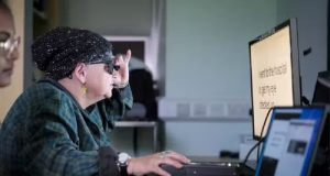 A britânica Sheila Irvine com olho biônico em frente a tela de computador, de perfil