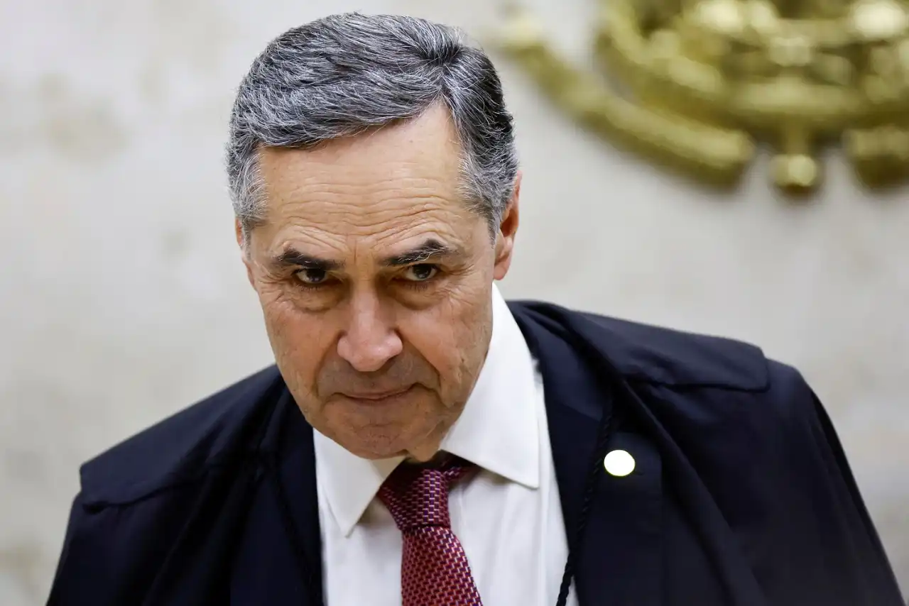 Luís Roberto Barroso com a cabeça baixa e sorriso tímido