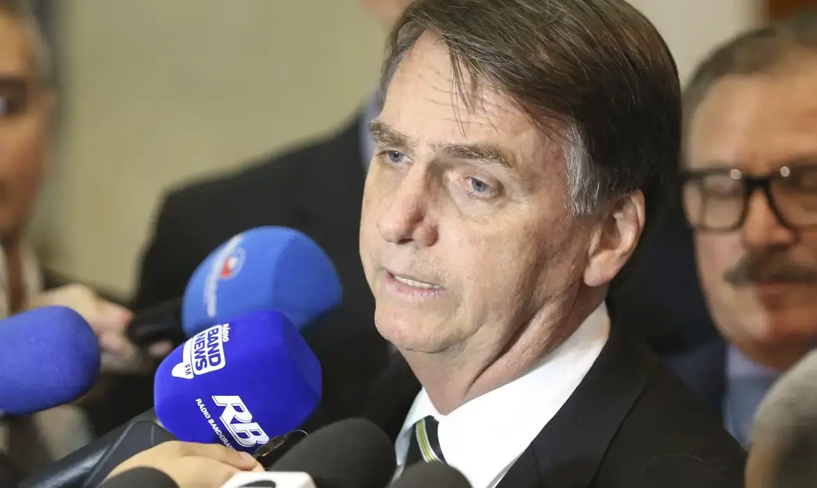 O ex-presidente Jair Bolsonaro (PL) em entrevista antiga, falando em microfones sem olhar para a câmera, sério