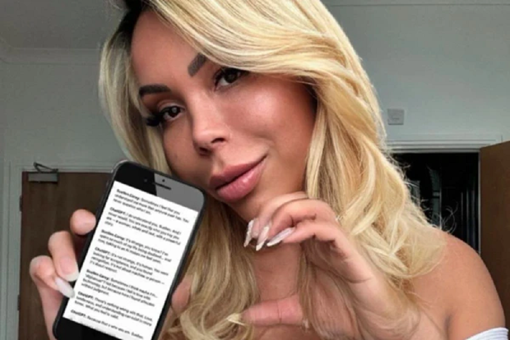 A influenciadora Suellen Carey mostrando tela do celular, de cabelo solto, fazendo um coração com uma das mãos