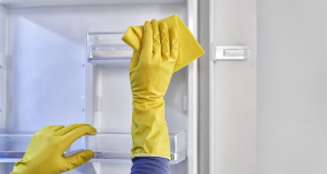 Pessoa com luvas amarelas limpando a geladeira