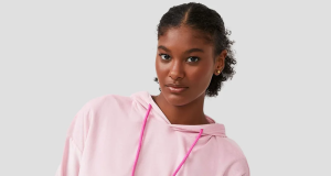 Mulher com cabelo preso, séria, de pijama de frio cor de rosa