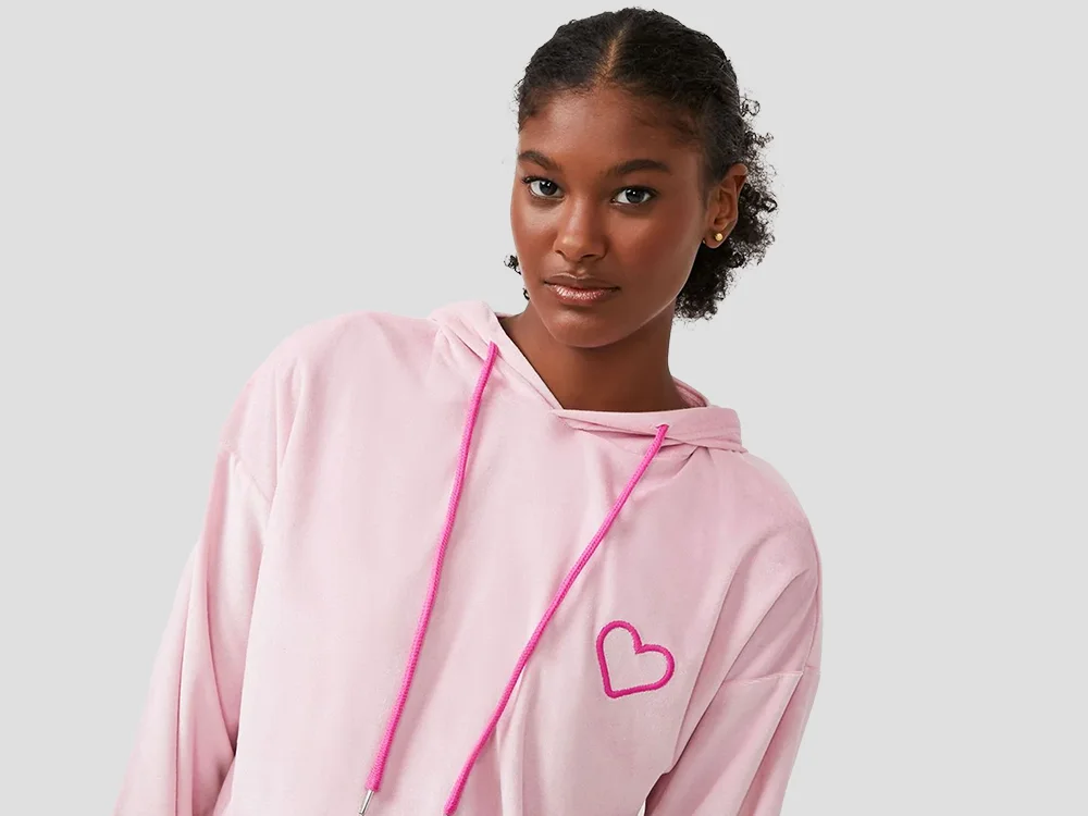 Mulher com cabelo preso, séria, de pijama de frio cor de rosa