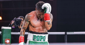 O tetracampeão mundial de boxe Acelino “Popó” Freitas cabisbaixo, no ringue, com short verde e branco e luvas vermelhas