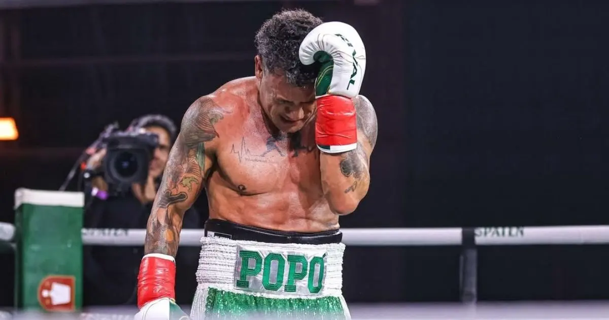 O tetracampeão mundial de boxe Acelino “Popó” Freitas cabisbaixo, no ringue, com short verde e branco e luvas vermelhas