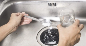 Sal e água sendo despejados em ralo de pia da cozinha