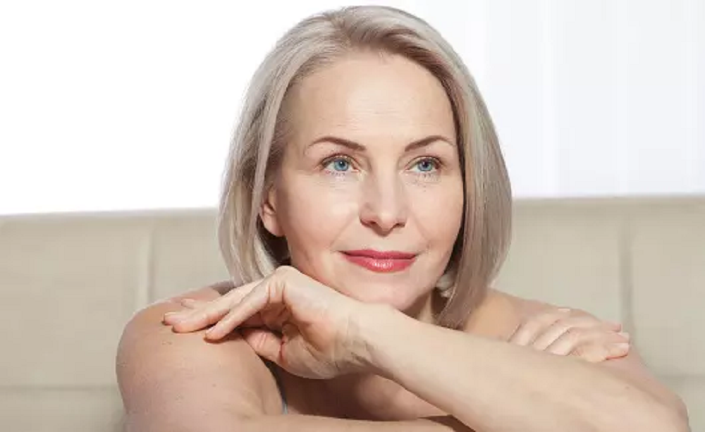 Mulher de cabelo curto e olhos claros, com expressão serena, sem olhar para a câmera