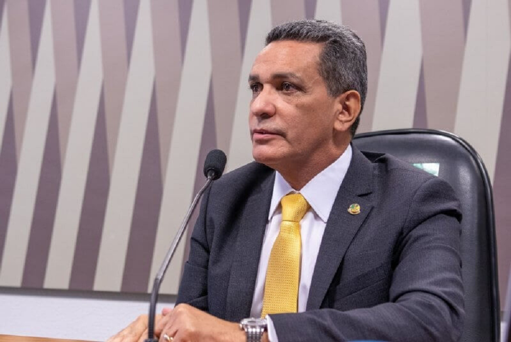 O senador Mecias de Jesus (RR) sentado, de perfil, falando, sério