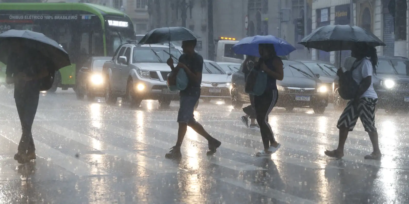 Pessoas com guarda-chuva andando na chuva em São Paulo
