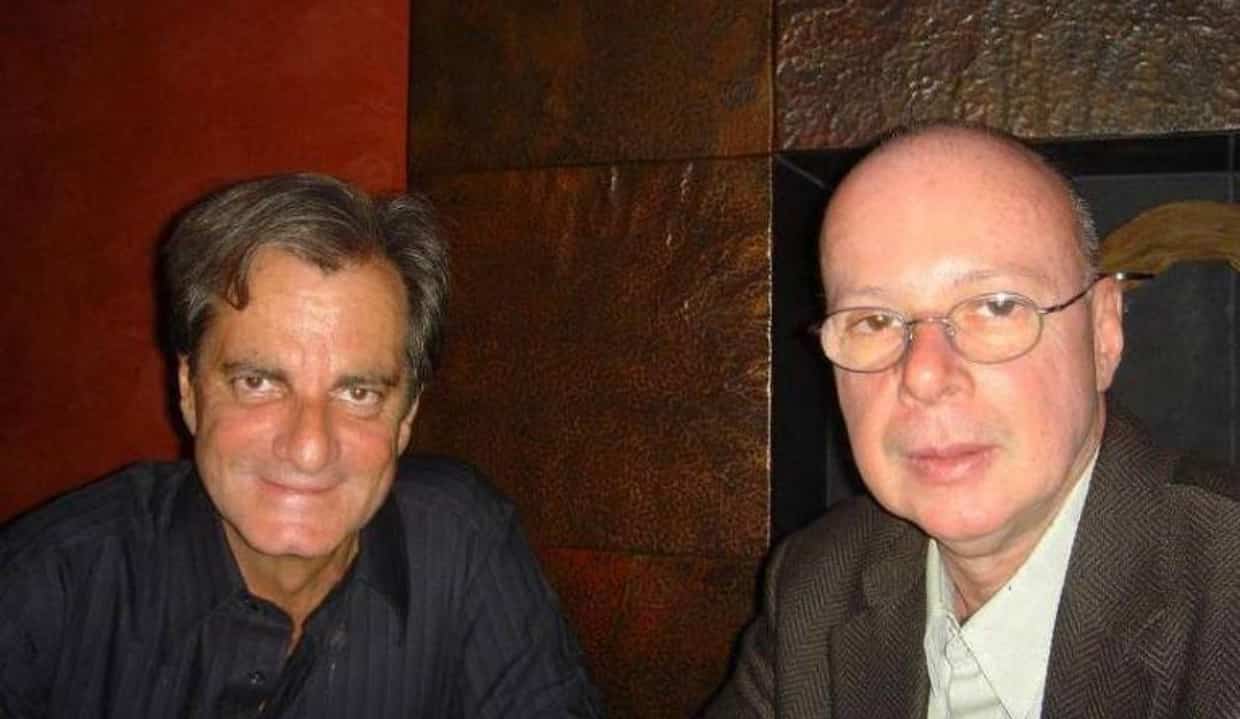 Edgar Moura Brasil e Gilberto Braga olhando para a câmera, lado a lado, o primeiro sorrindo e o segundo sério e de óculos