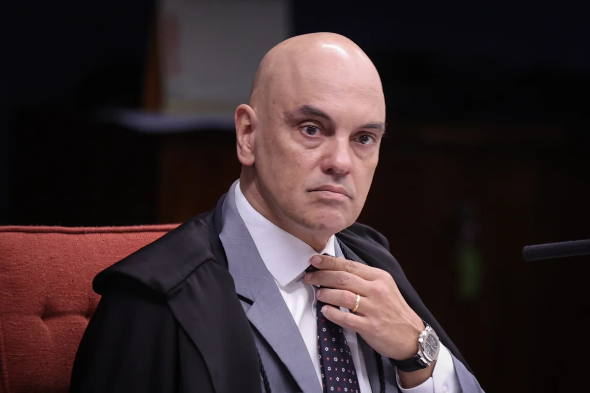 O ministro Alexandre de Moraes, do STF, com expressão distraída e mexendo na gravata