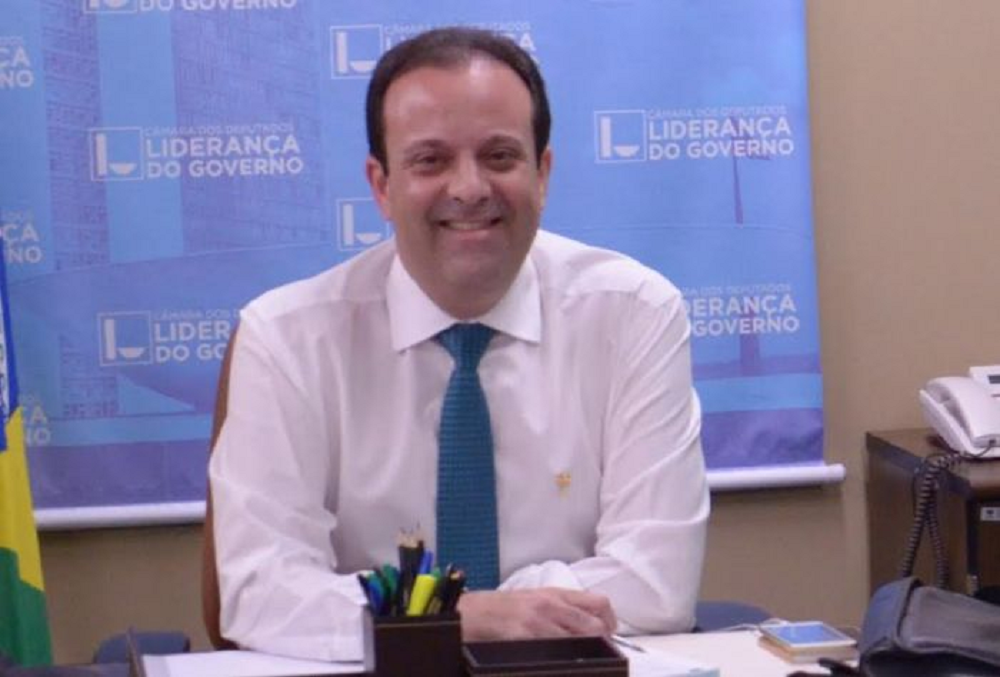 André Moura, da Secretaria de Governo do RJ, sorrindo, sentado, olhando para a câmera
