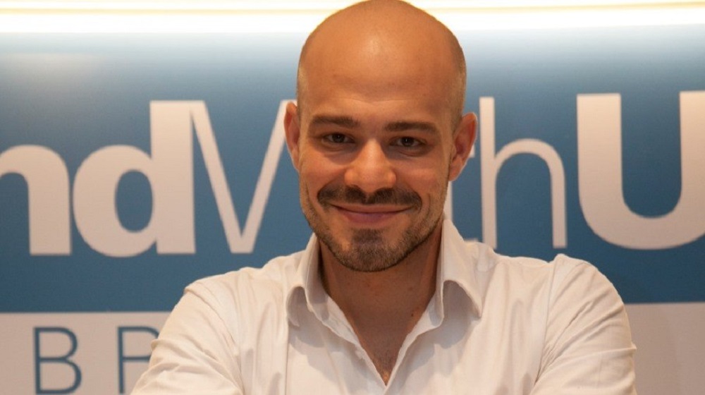 cientista político André Lajst olhando para a câmera com sorriso tímido