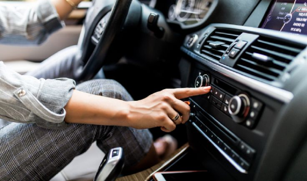 Mulher ligando ar-condicionado de carro, só braços e pernas aparecendo