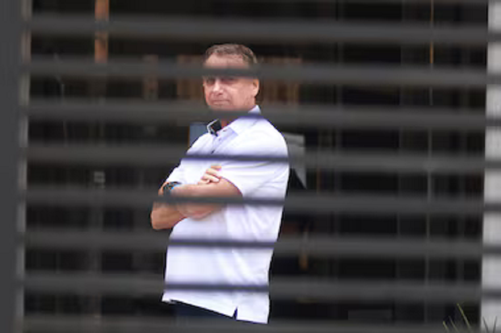 Jair Bolsonaro em prisão domiciliar, de braços cruzados, de roupa branca