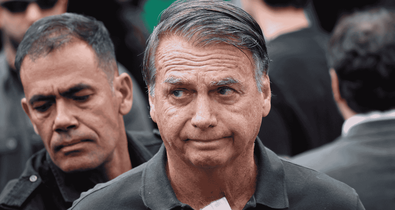 Jair Bolsonaro (PL) olhando levemente para o lado, sério, cercado de pessoas