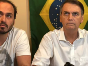 O vereador Carlos Bolsonaro (PL-RJ) e o ex-presidente Jair Bolsonaro (PL) sentados lado a lado, sérios, de roupas brancas, sem olhar para a câmera