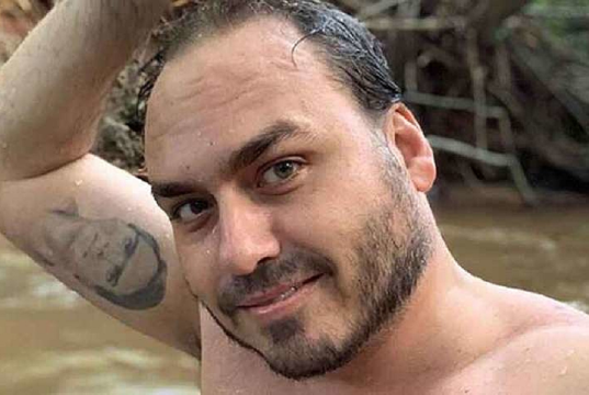 Carlos Bolsonaro sem camisa, molhado, com um dos braços levantados