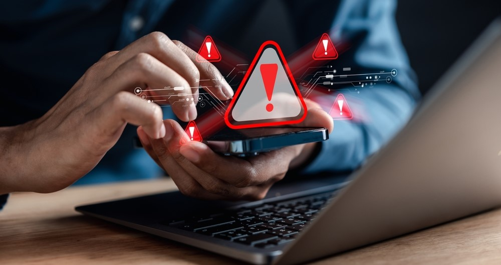 Mãos mexendo em celular perto de notebook