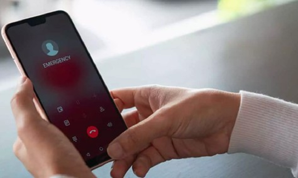 Mão segurando celular com tela aberta em ligação de emergência