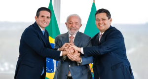 Hugo Motta, Lula e Davi Alcolumbre lado a lado, sorrindo em aperto de mãos