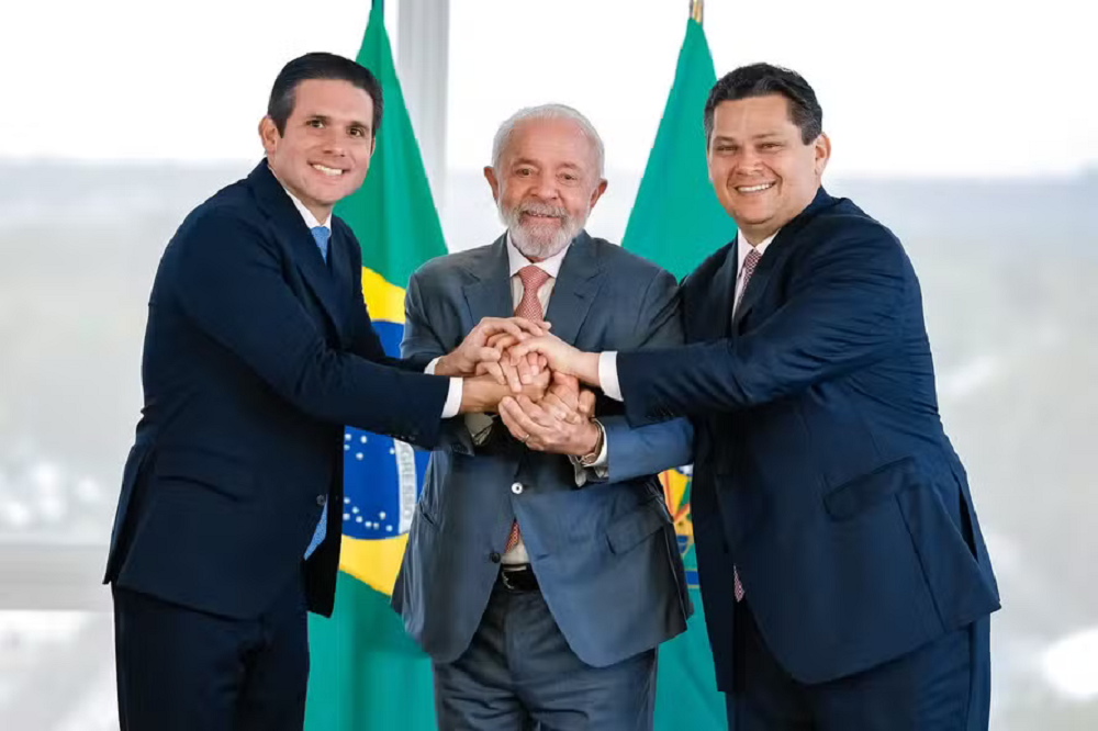 Hugo Motta, Lula e Davi Alcolumbre lado a lado, sorrindo em aperto de mãos