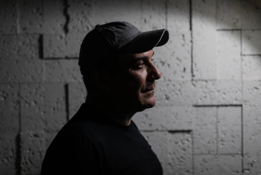 O delegado aposentado Orlando Zaccone, da Policia Civil do RJ, de perfil, de boné, sério, em foto sombreada