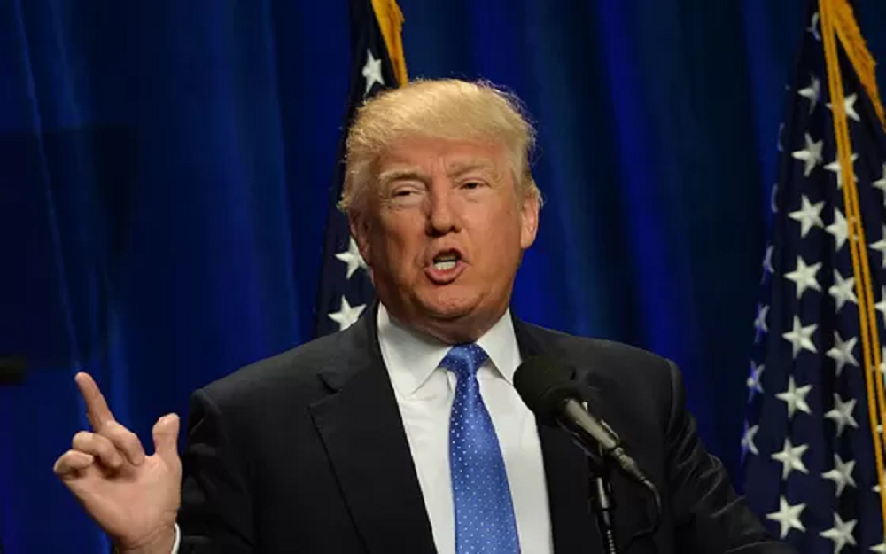 presidente Donald Trump falando e apontando pra cima, sem olhar para a câmera