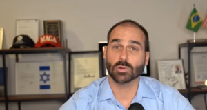 O deputado Eduardo Bolsonaro (PL-SP) de roupa social azul clara, falando para a câmera