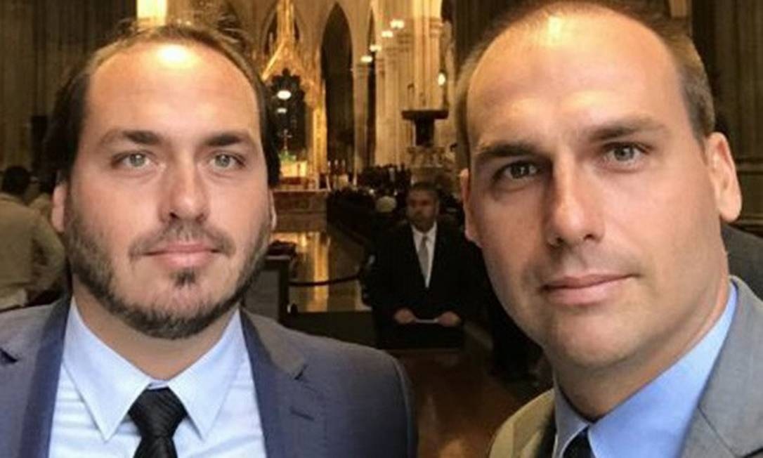 O vereador Carlos Bolsonaro e o deputado Eduardo Bolsonaro sérios, em selfie