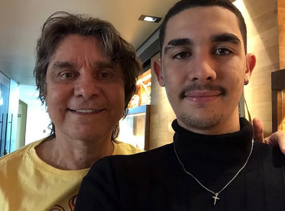 Lô Borges ao lado do filho Luca Arroyo Borges, posando para foto e sorrindo