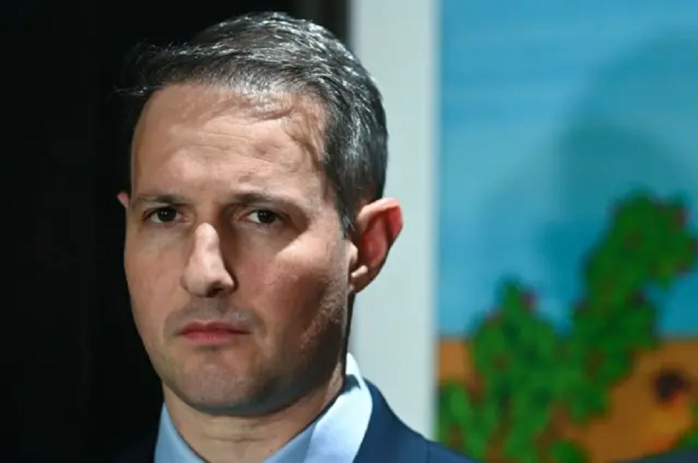 Guilherme Derrite sério, olhando para a câmera, em close