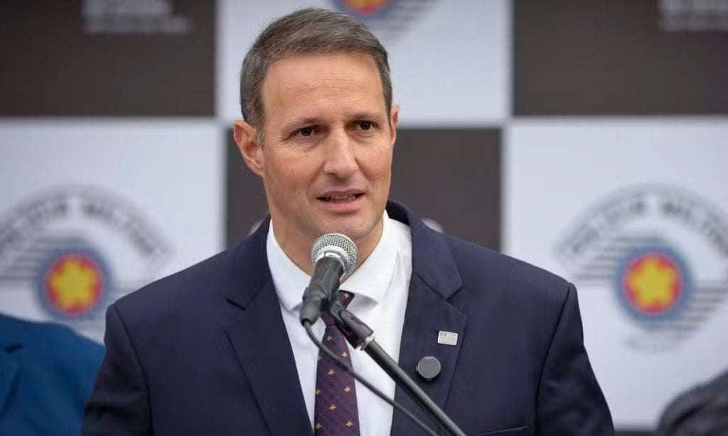 deputado Guilherme Derrite (PP-SP) sério, falando em microfone, sem olhar para a câmera