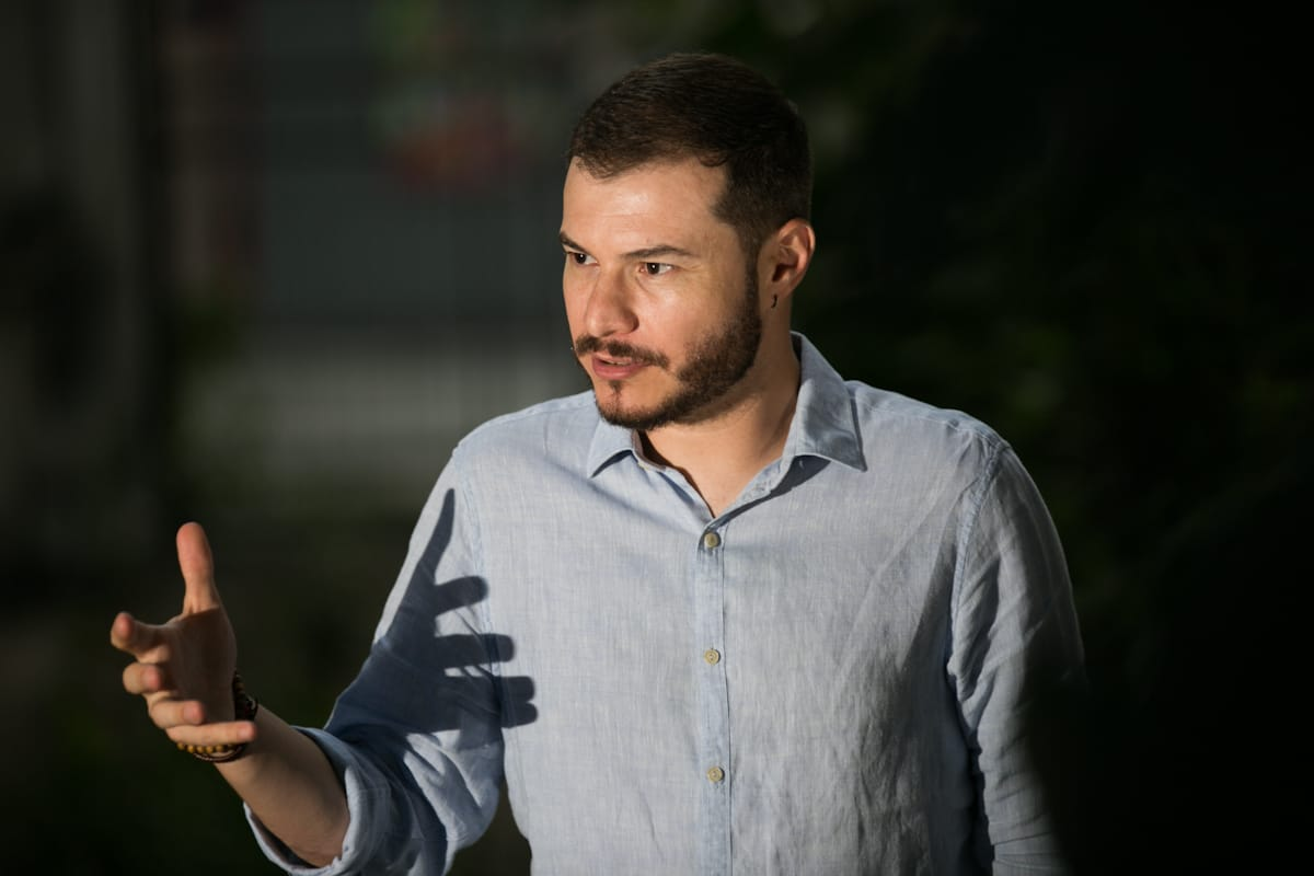 Juliano Medeiros, doutor em Ciência Política pela Universidade de Brasília, falando e gesticulando, olhando para o lado, de roupa social clara